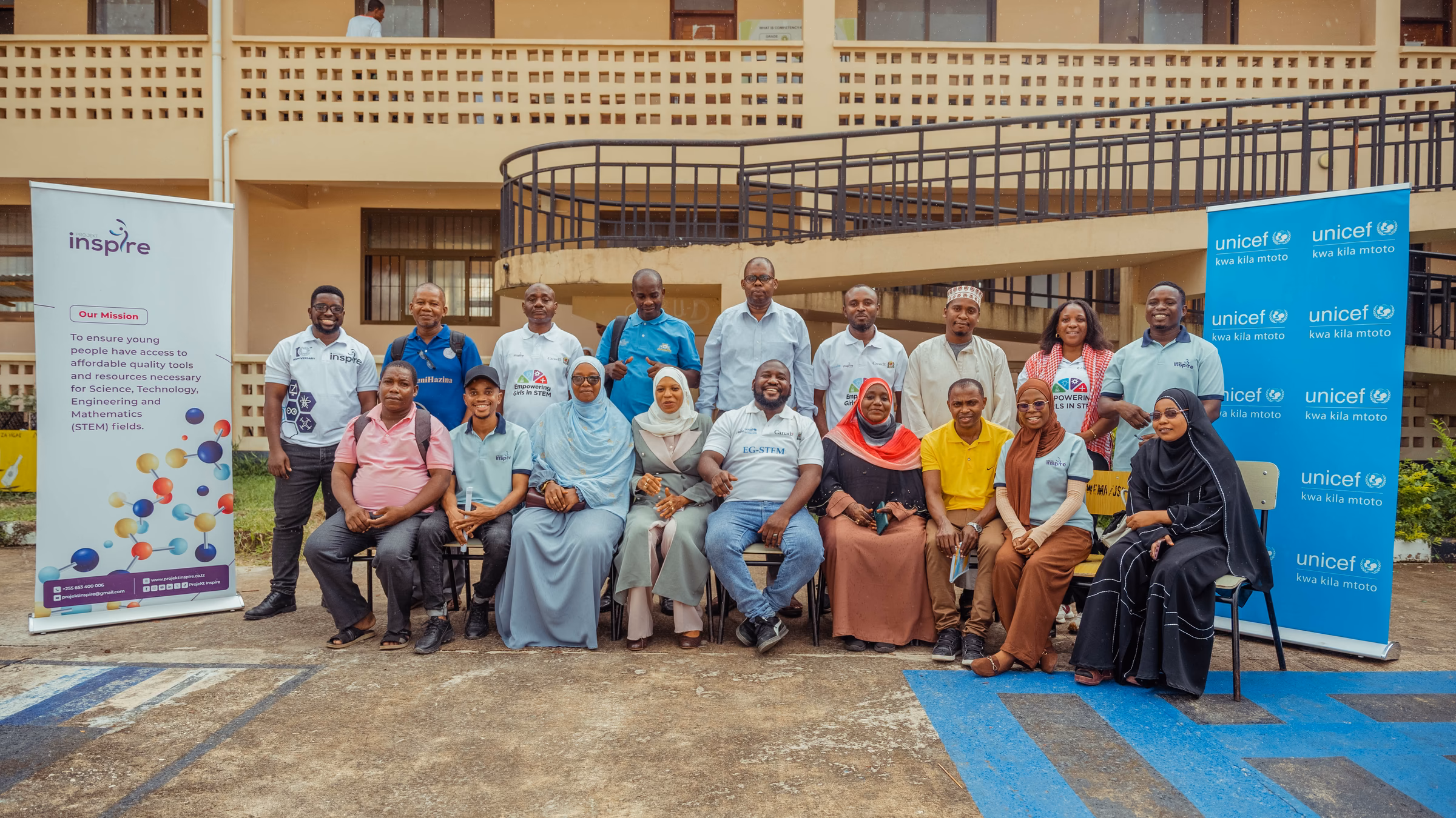 A group portrait between Projekt Inspire and UNICEF banners in Unguja