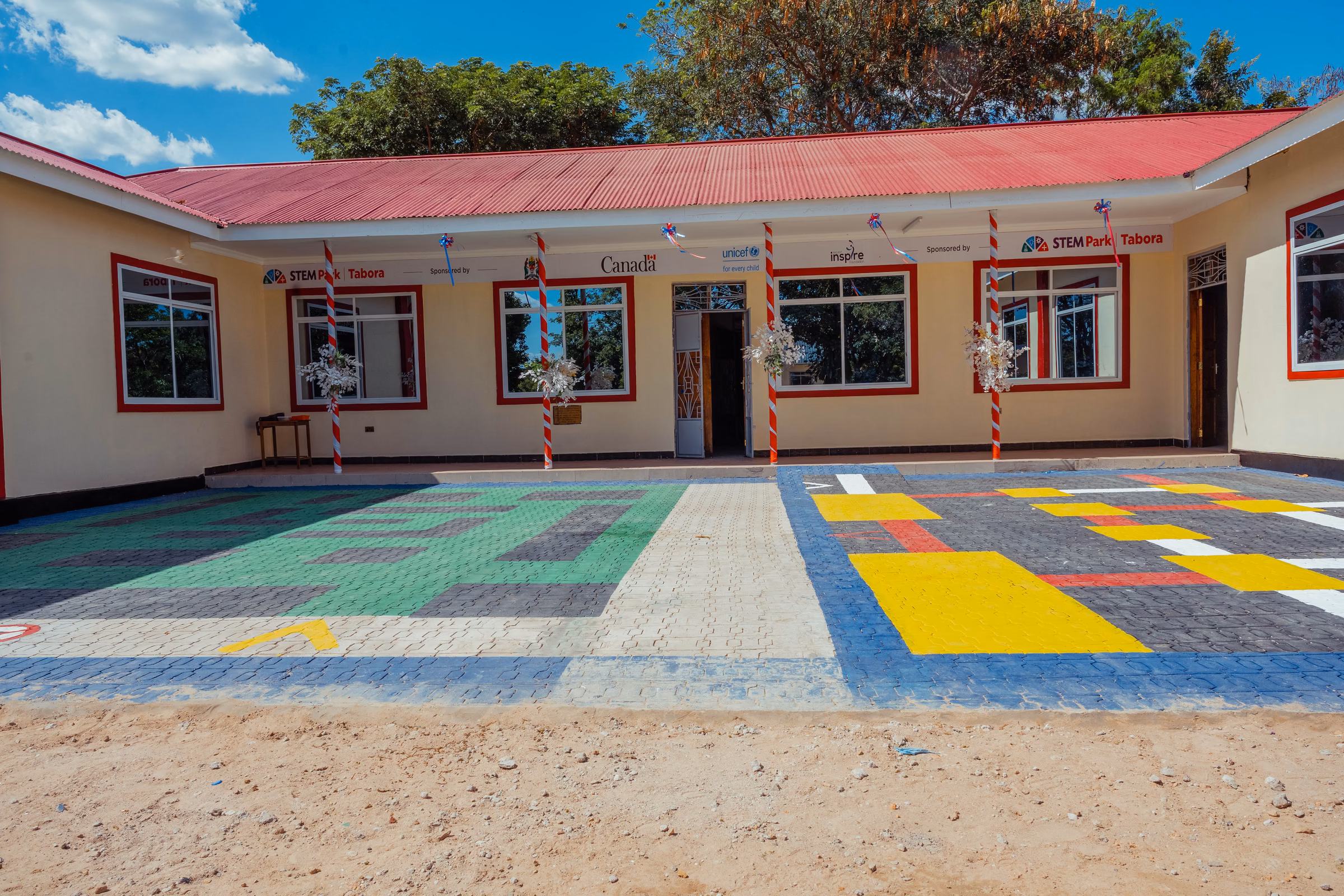 The courtyard and entrance of STEM Park Tabora, with colourful learning patterns painted across the paving