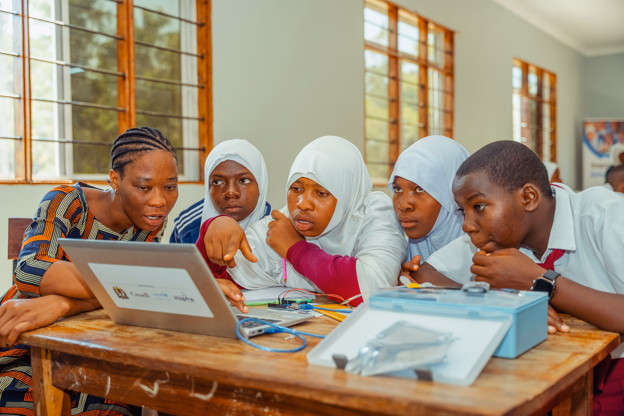 A facilitator guiding students through a laptop-based STEM activity